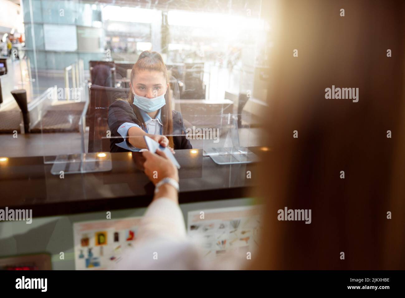 Signora che dà il passaporto ad un ufficiale e aspetta la sua carta d'imbarco Foto Stock