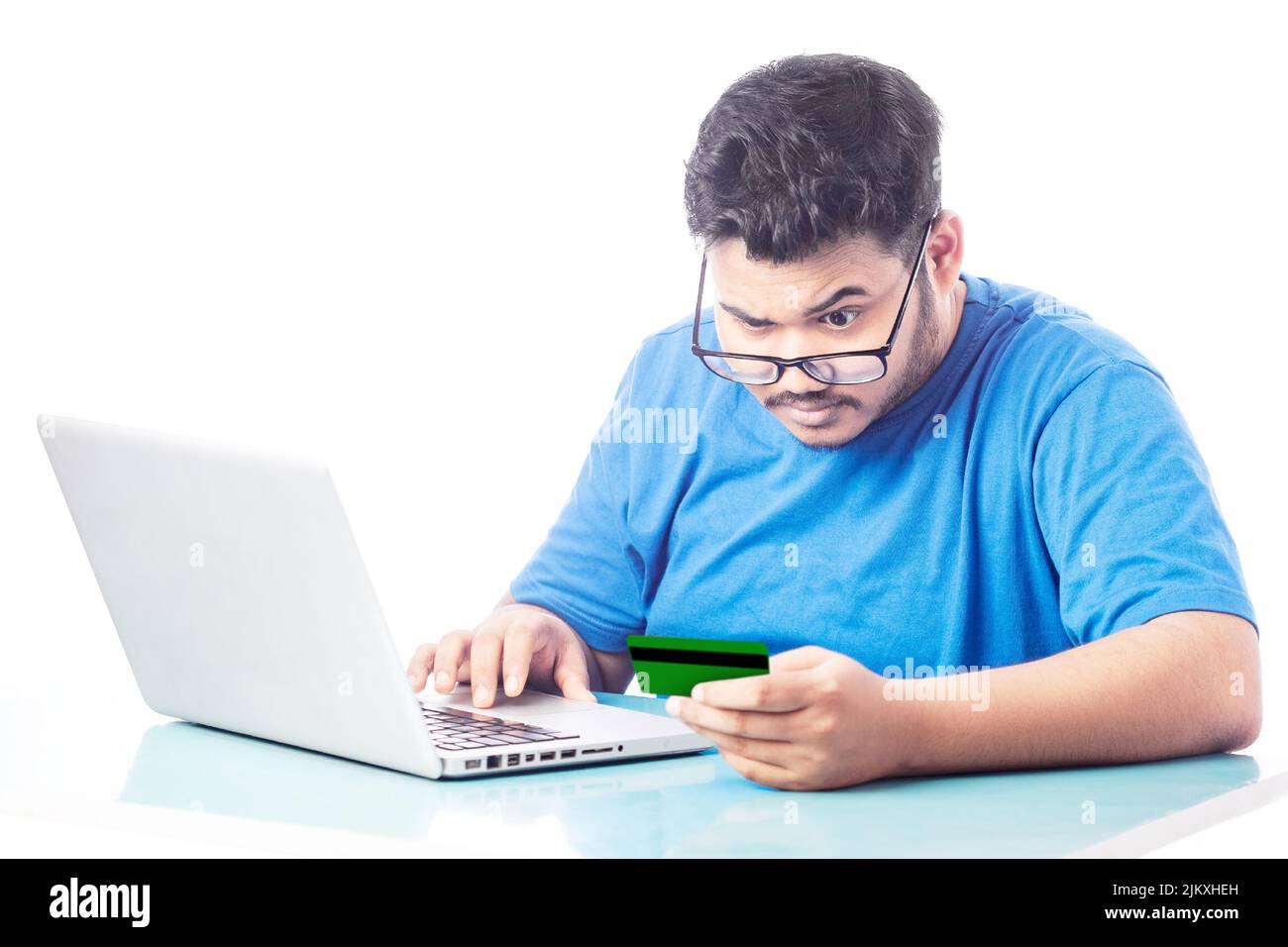giovane uomo che indossa occhiali leggere le informazioni della carta di credito per il pagamento online della fattura dal conto Foto Stock