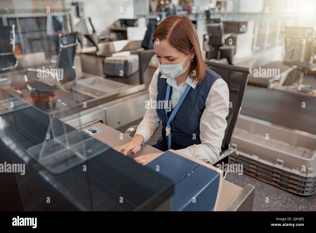 Dipendente dell'aeroporto femminile seduto sul posto di lavoro e a dattilografia Foto Stock