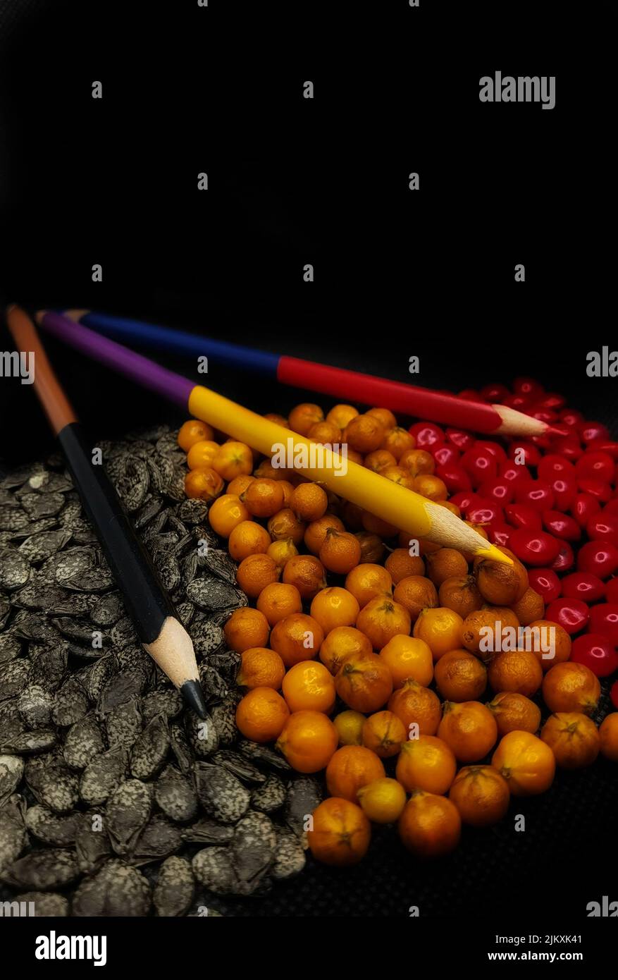 Matite di colore rosso, giallo e nero con semi dello stesso colore Foto Stock