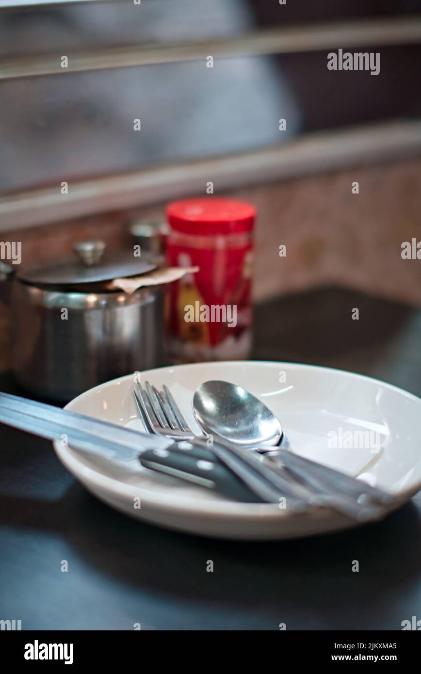 Una forchetta e un cucchiaio con coltello in piatto bianco su un tavolo in un ristorante Foto Stock