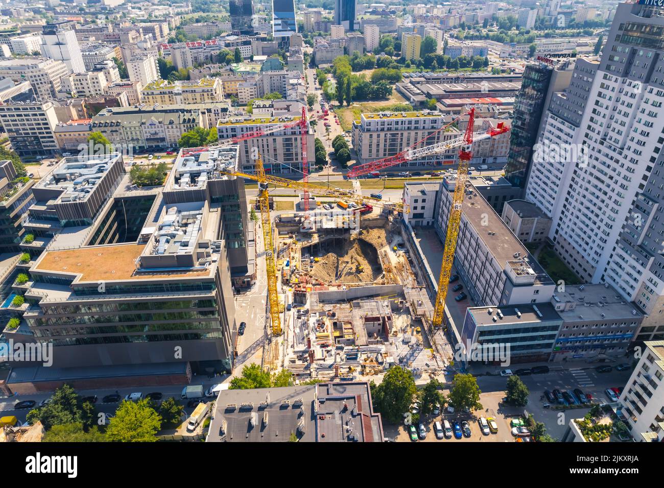 Concetto di architettura eclettica. Costruzione di un grattacielo o di un blocco di appartamenti. Tre autogru professionali e lavoratori edili che svolgono il loro lavoro. Vista aerea. . Foto di alta qualità Foto Stock