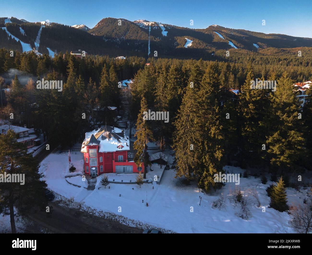 Una bella vista ad angolo alto di una piccola casa der building in una foresta su un terreno coperto di neve Foto Stock