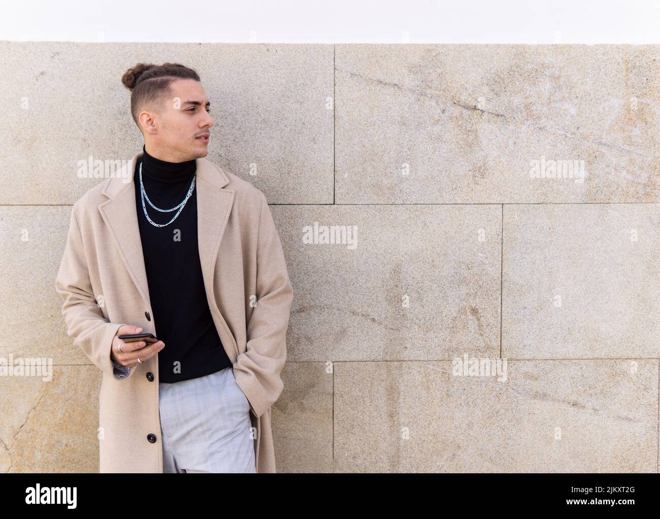 Ritratto di un giovane uomo misto che tiene uno smartphone in città. Social media, comunicazione, app mobili, business, concetto di stile di vita Foto Stock