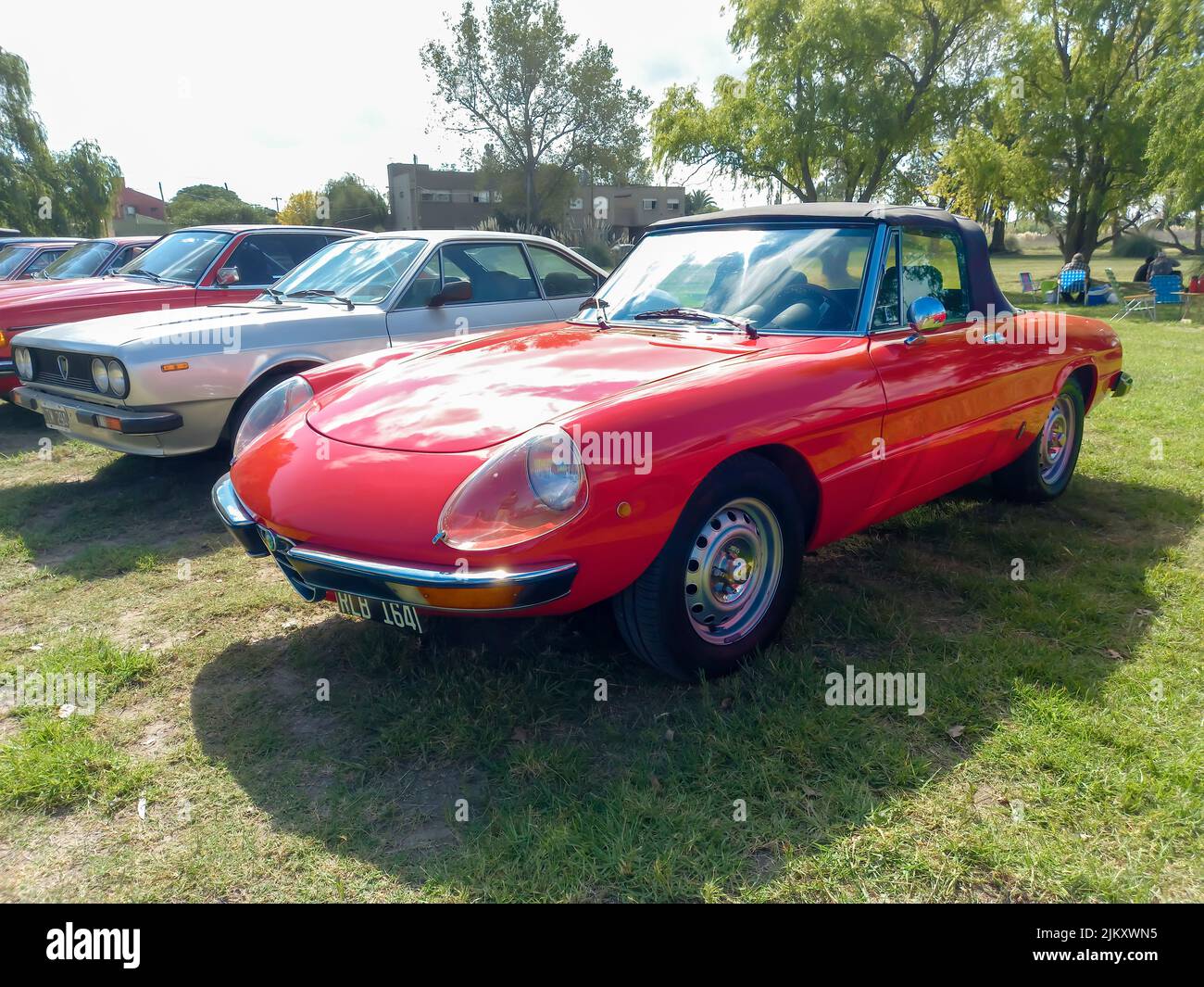 Chascomus, Argentina - Apr 9, 2022: Red sport Alfa Romeo Spider Veloce Roadster Series 2 coda Tronca 1970s parcheggiato sull'erba. Alberi natura nella ba Foto Stock