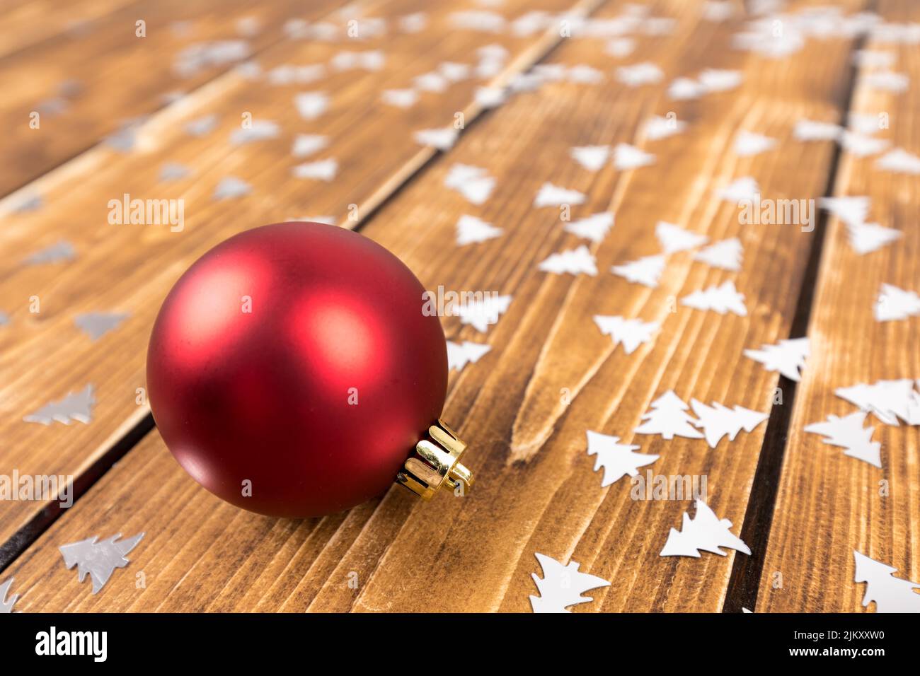 Un primo piano di un giocattolo rosso dell'albero di Natale su un tavolo di legno Foto Stock