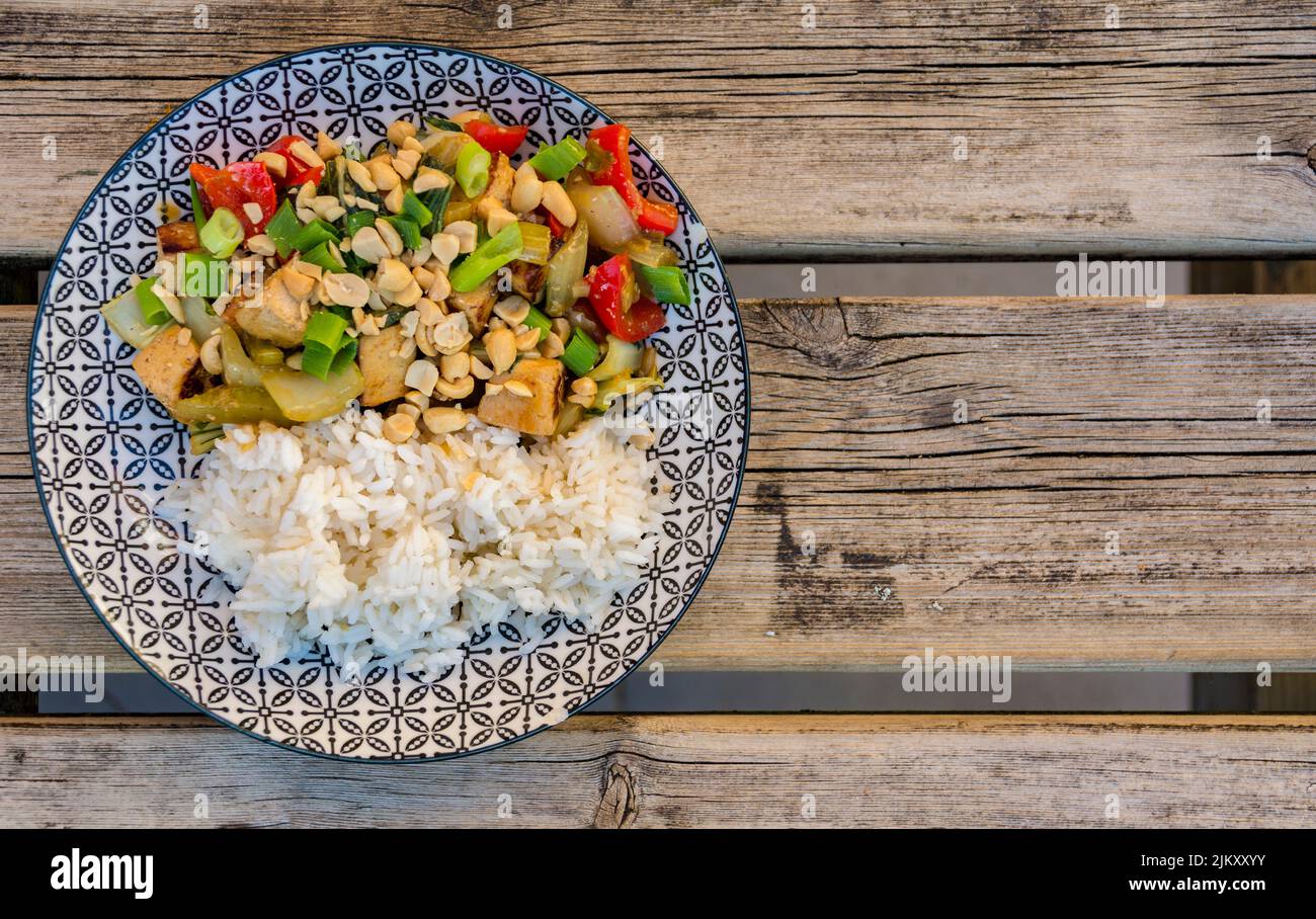 Piatto asiatico vegano con tofu, verdure e riso su tavola di legno intemperie. Cibo gustoso. Foto Stock