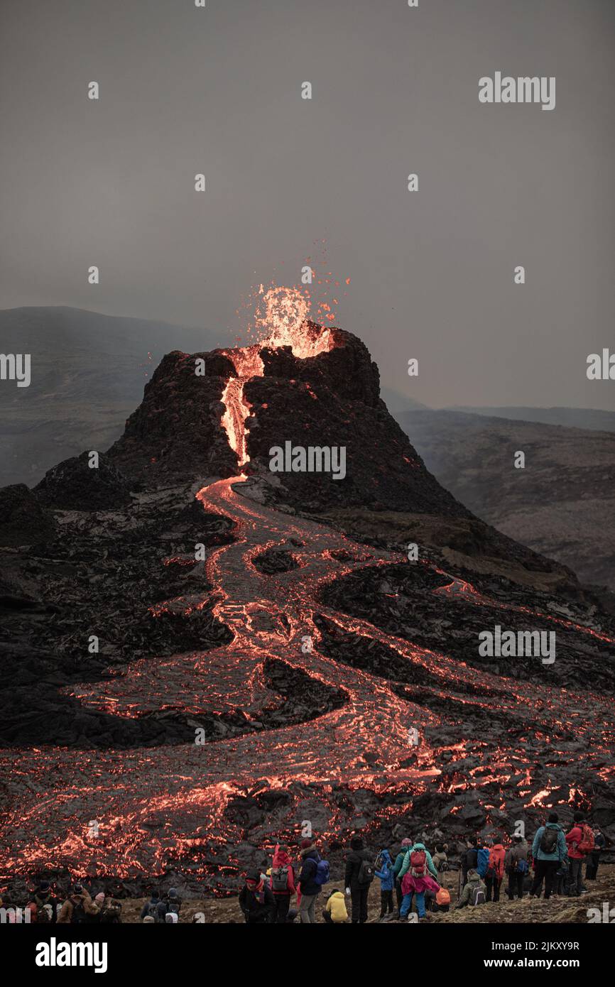 Una vista serale dell'eruzione del vulcano in Islanda. La gente guarda il fiume ardente Foto Stock