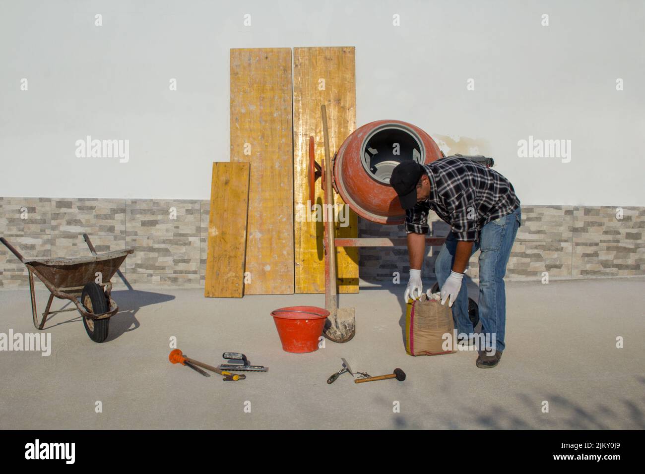 Immagine di un muratore che apre un sacco di cemento mentre rinnova una casa. Lavoro fai-da-te Foto Stock