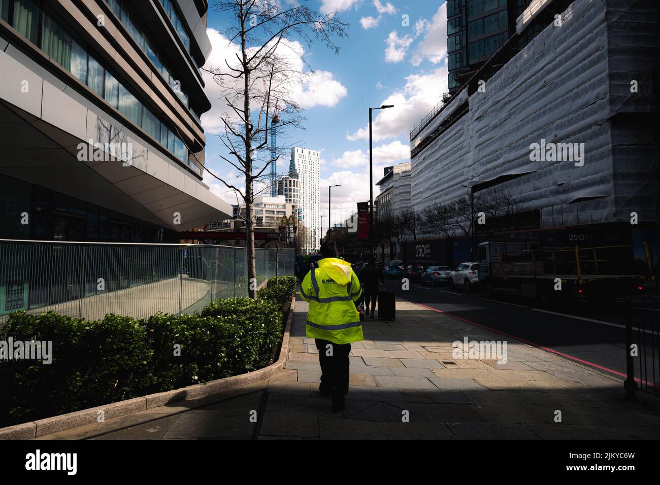 Una bella foto di una persona che indossa una giacca di sicurezza per un luogo di lavoro e che cammina per strada Foto Stock