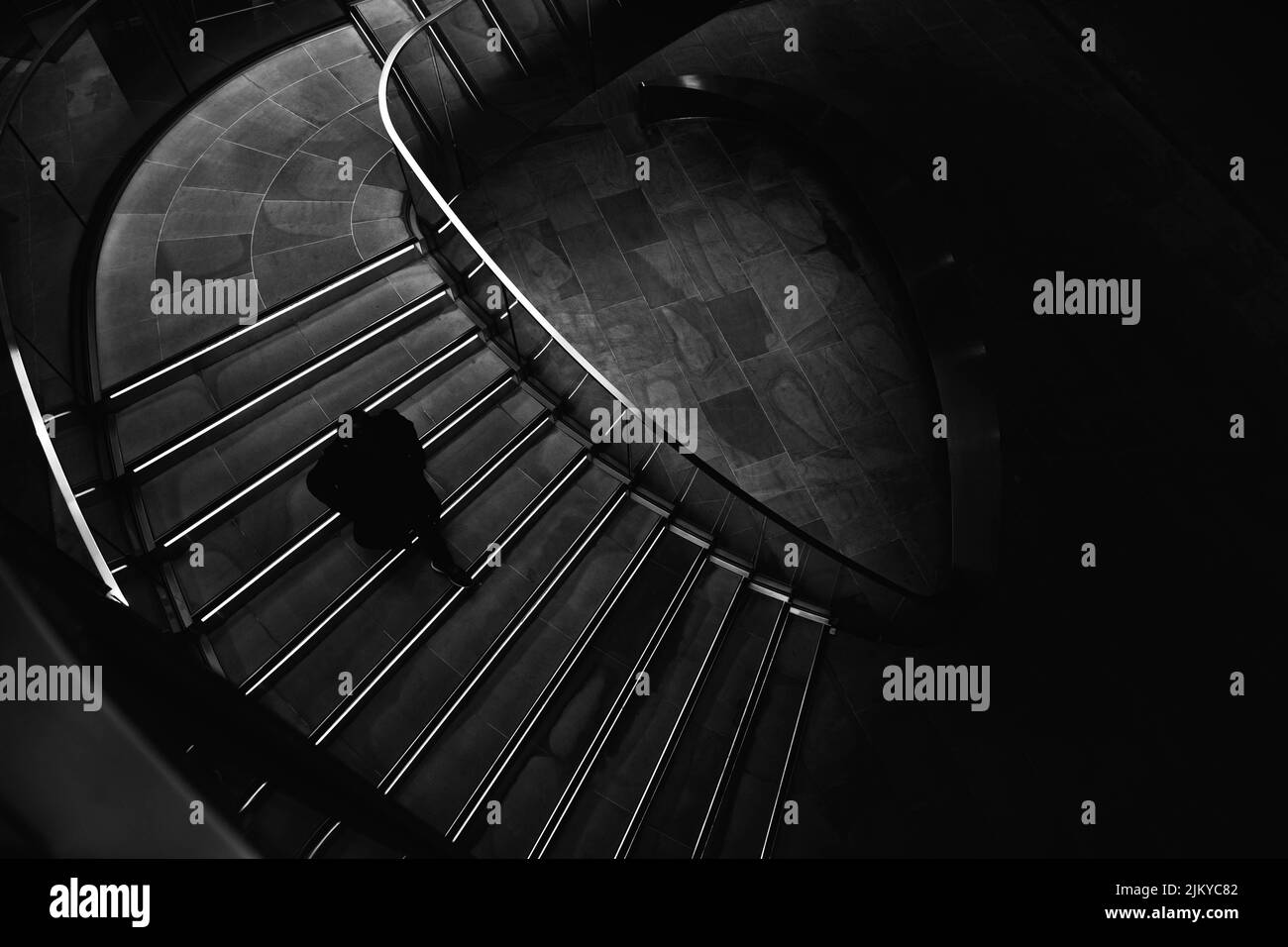 Una vista in scala di grigi di una persona che scende le scale in un edificio Foto Stock