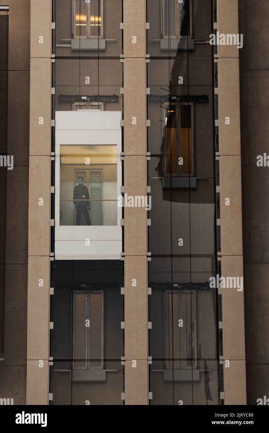 Un'immagine verticale di un uomo in un ascensore di vetro all'interno di un edificio moderno Foto Stock