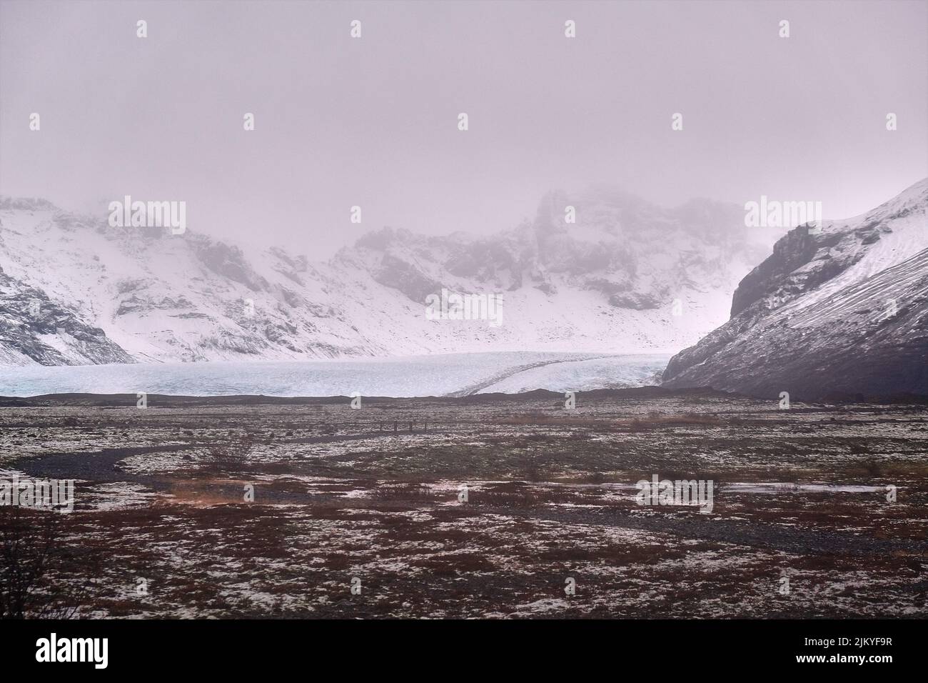 Ghiacciaio lontano visto fiancheggiato da montagne innevate nel sud dell'Islanda Foto Stock