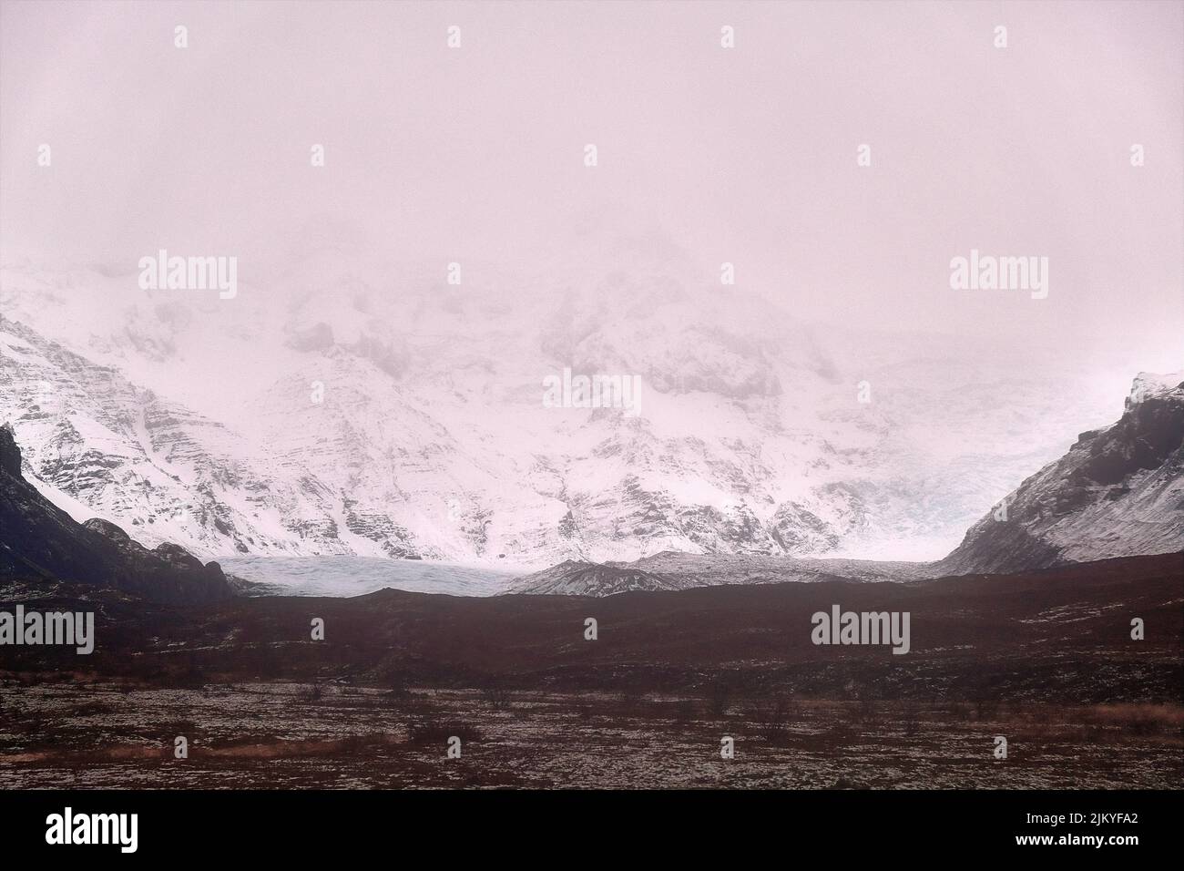 Montagne innevate che circondano la fine di un ghiacciaio nel sud dell'Islanda. Foto Stock