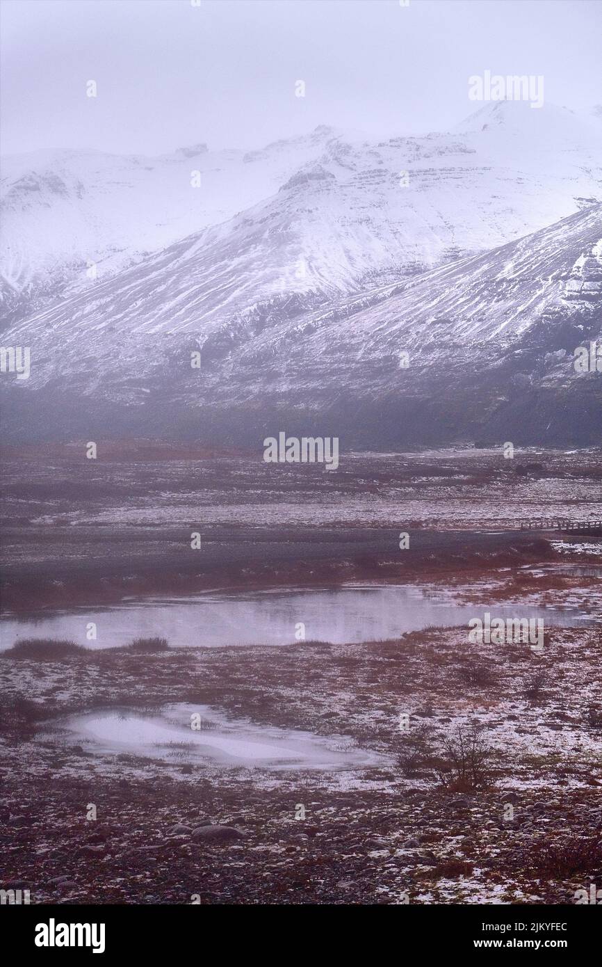 Montagne sormontate di neve. Stagni e paludi in primo piano. Sud Islanda vicino a Fjallsarlon e Jokulsarlon Foto Stock