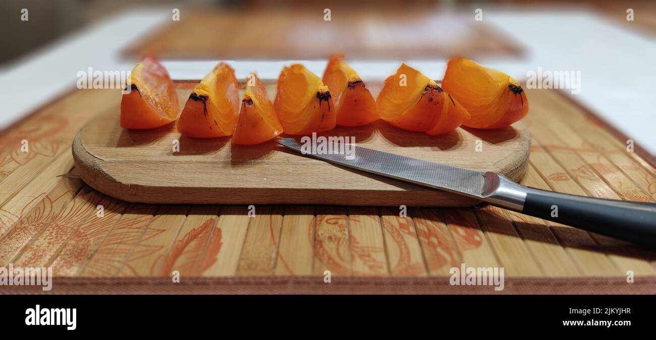 Un primo piano di Tut persimmon su un asse di legno Foto Stock