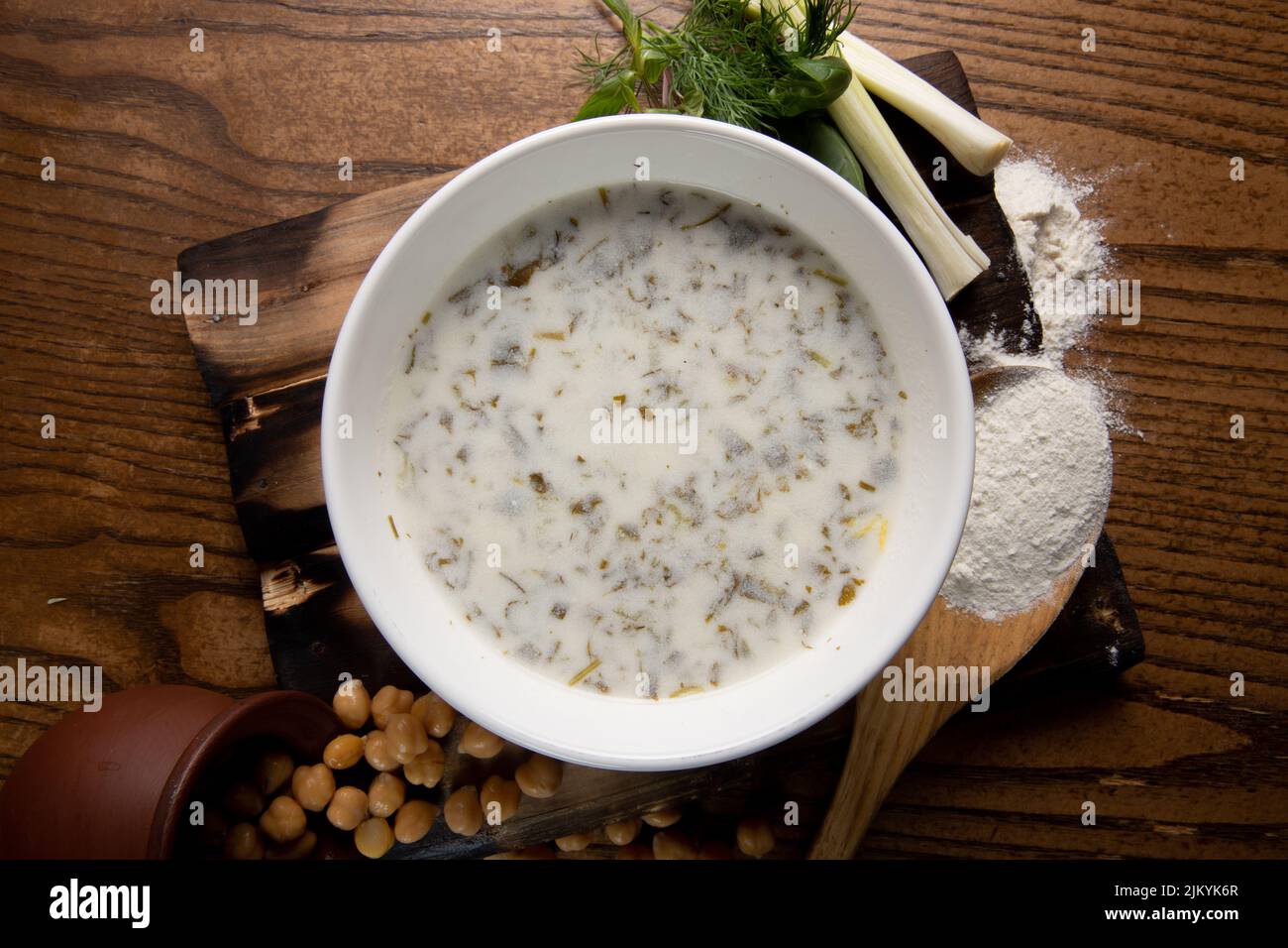 Una foto dall'alto di una zuppa di latte o di un porridge con fagioli che si versano da una pentola su un tavolo di legno Foto Stock