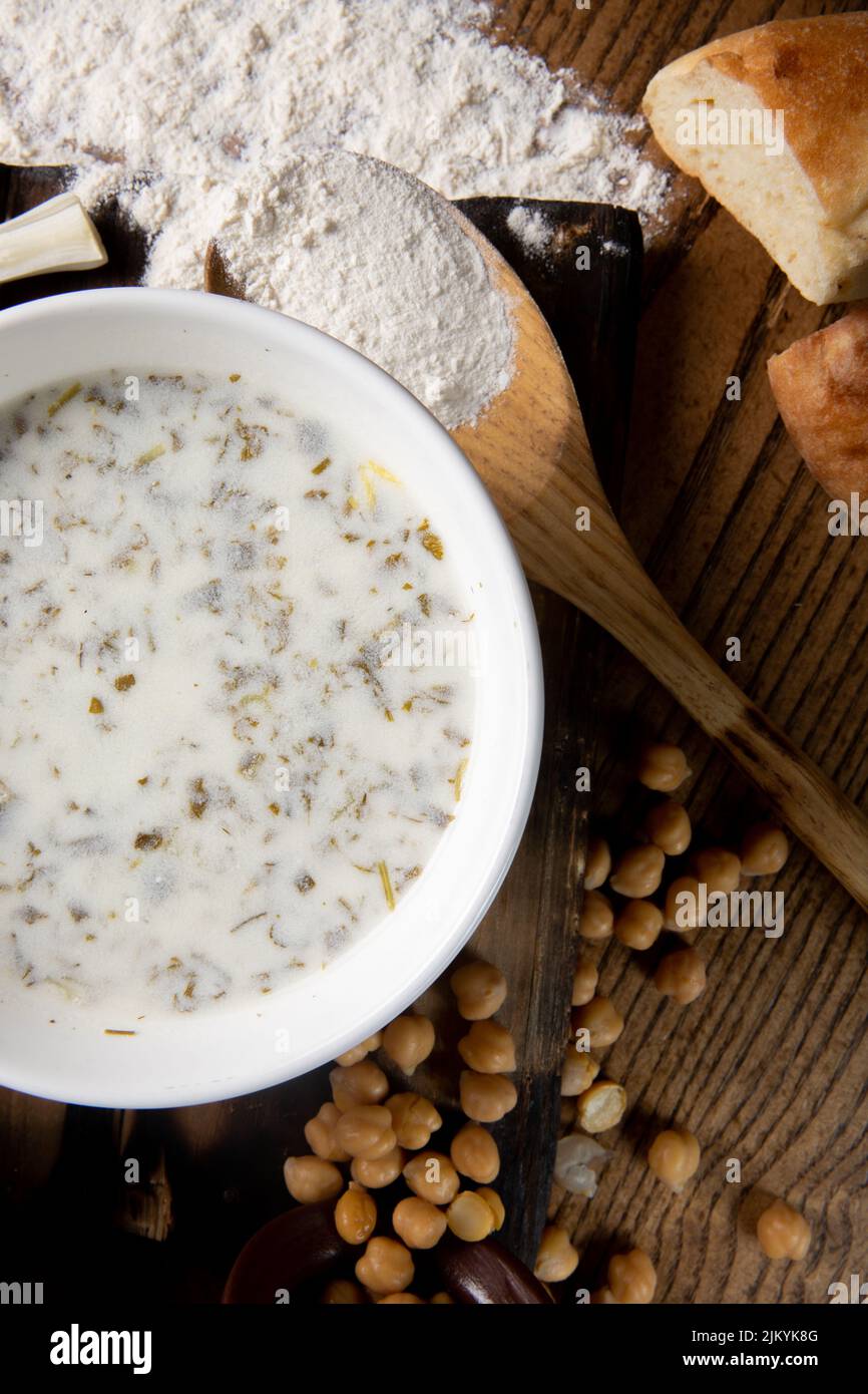 Una foto dall'alto di una zuppa di latte o di un porridge con fagioli che si versano da una pentola e pane su un tavolo di legno Foto Stock
