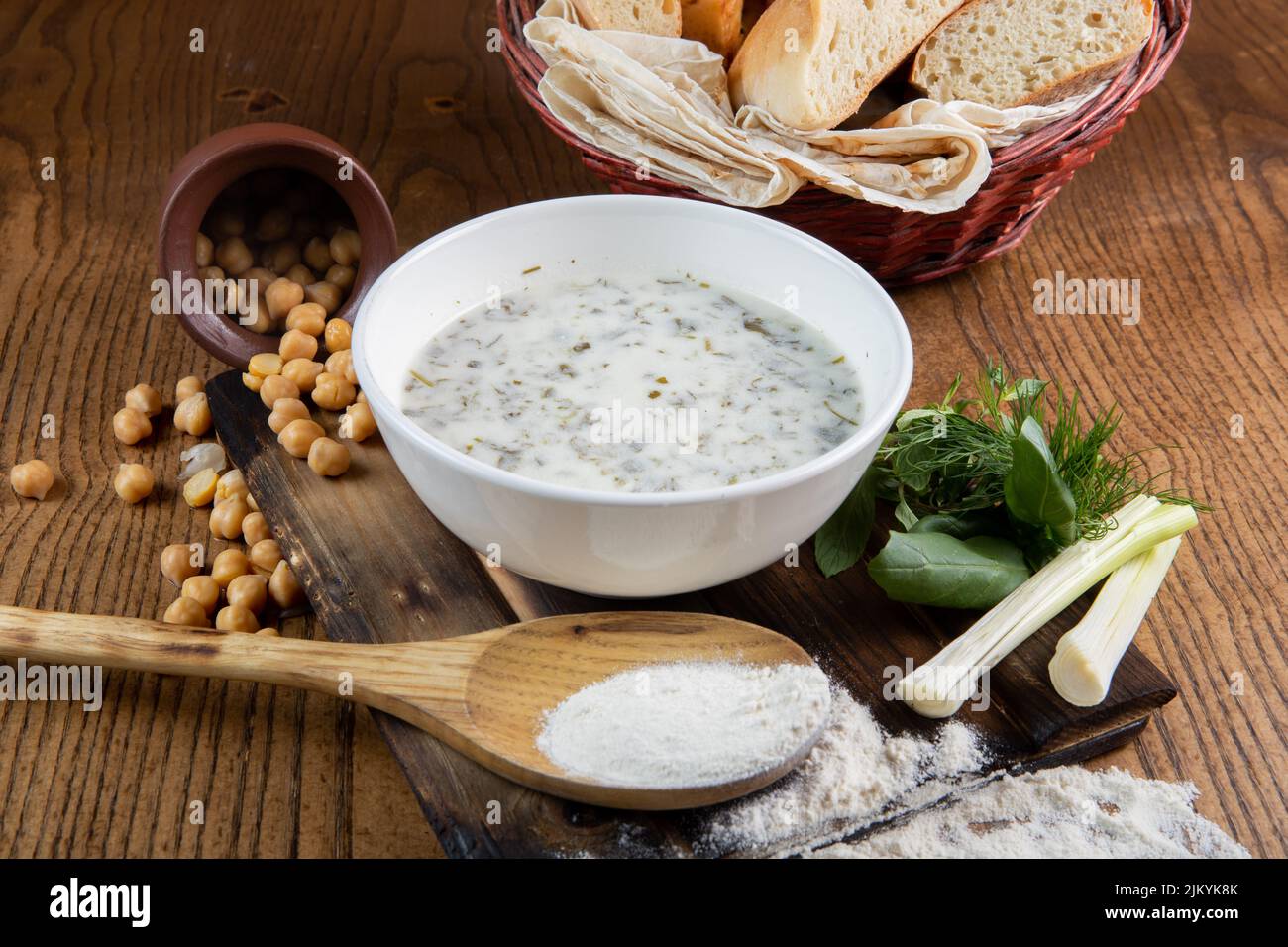 Una vista di una zuppa di latte o porridge con fagioli che si versano da una pentola e pane su un tavolo di legno Foto Stock