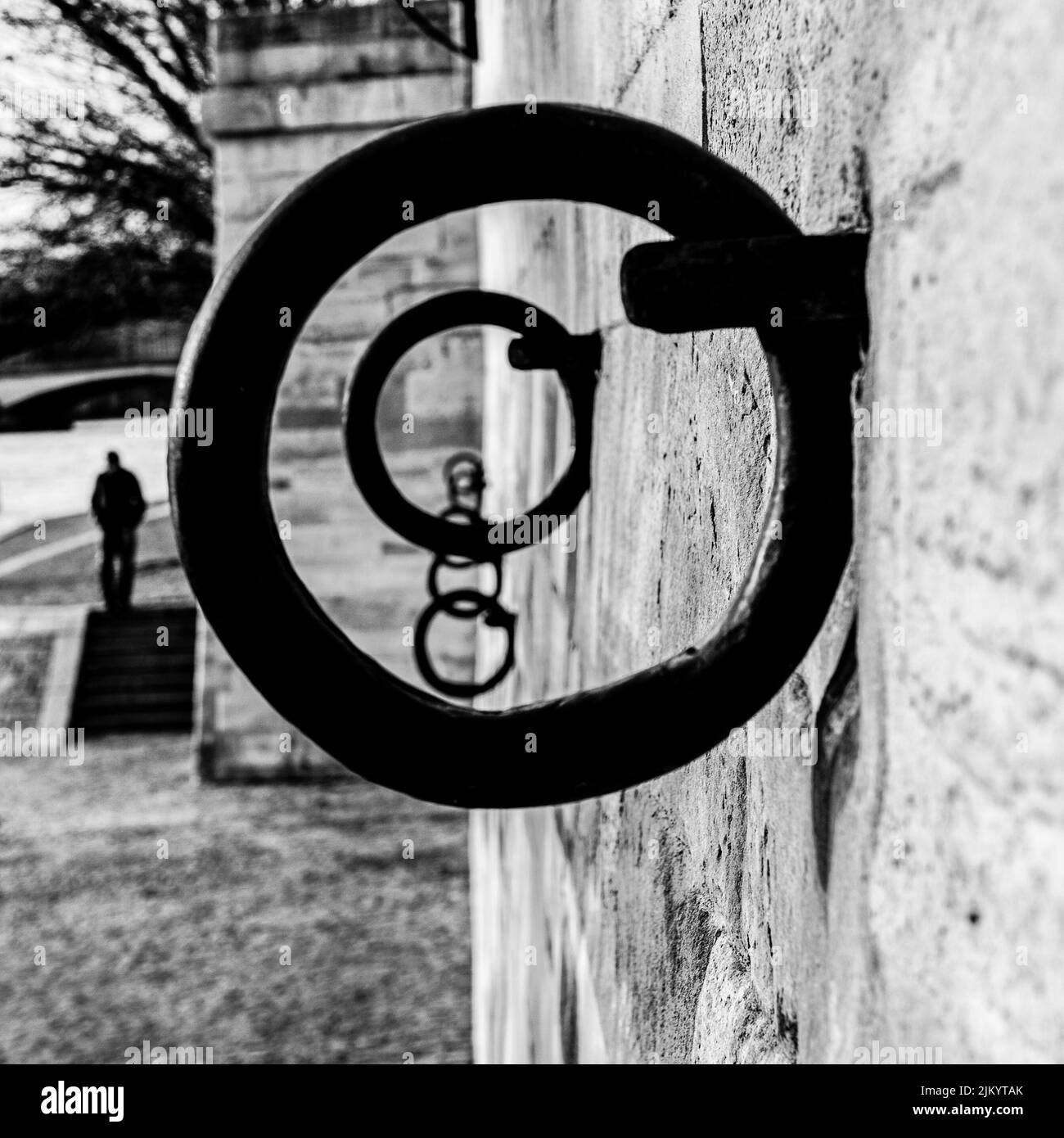 Un colpo in scala di grigi di anelli di ferro montati su pareti di cemento dal fiume Foto Stock