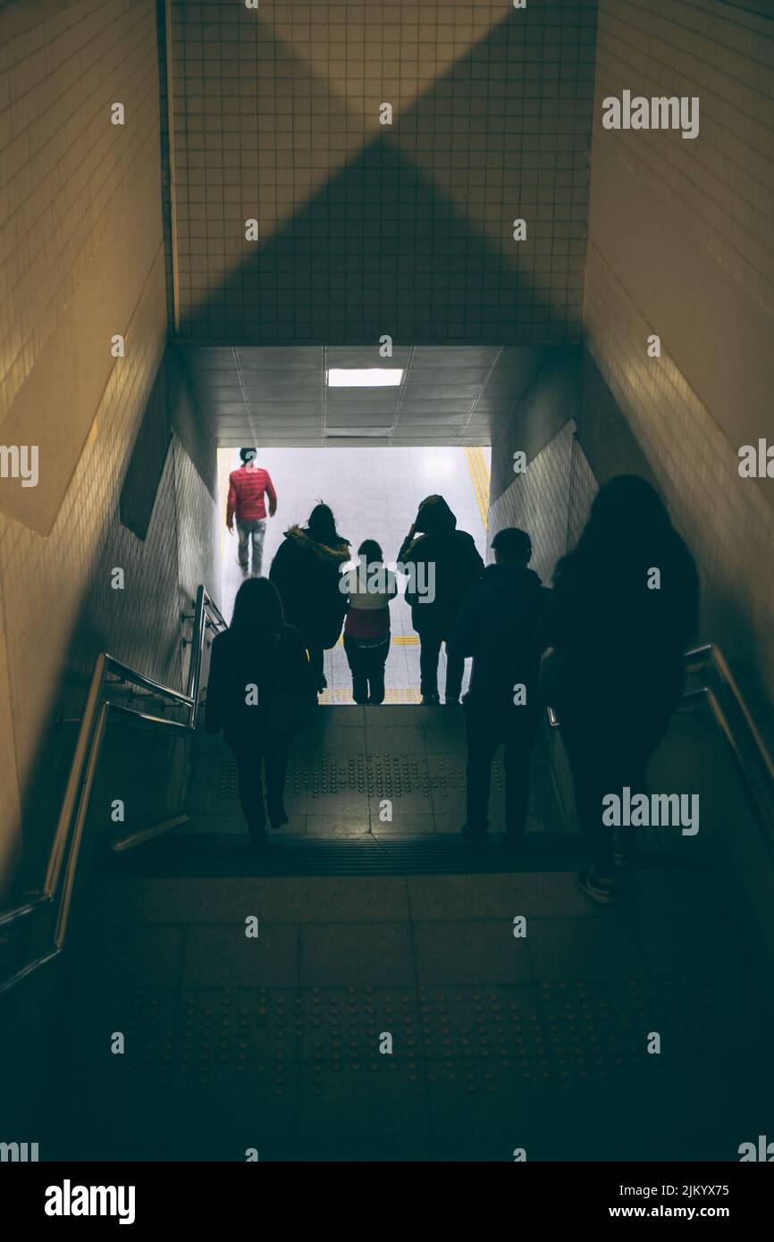 Una vista sul retro di persone che camminano su una scala sotterranea Foto Stock