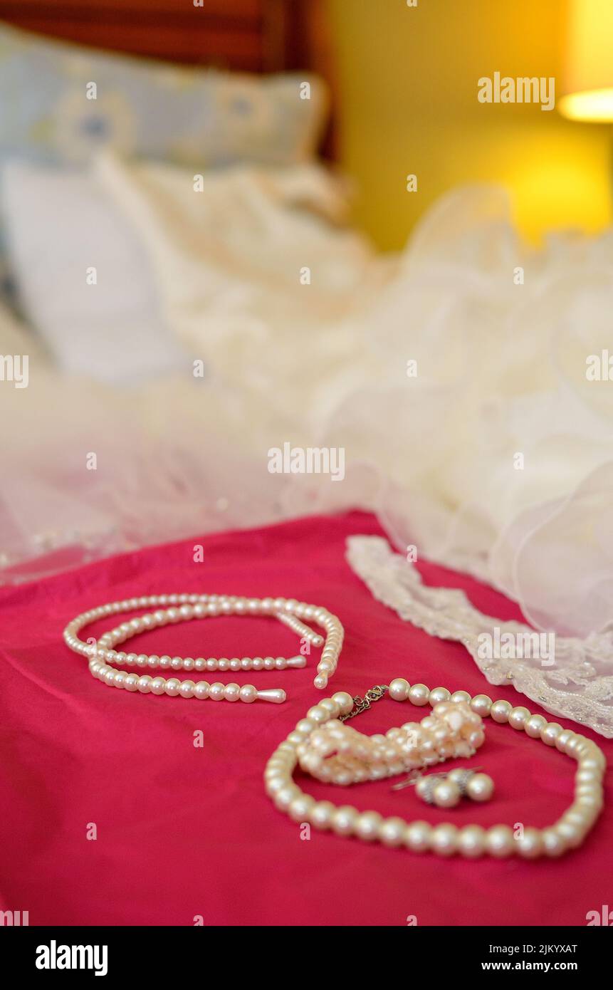 Una foto verticale di gioielli in perla su un letto su uno sfondo sfocato Foto Stock