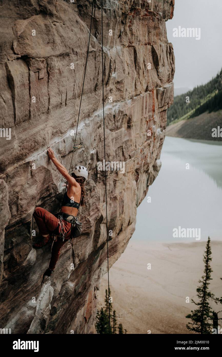 Il primo piano di una donna adulta arrampicatrice su una scogliera vicino a un lago Foto Stock