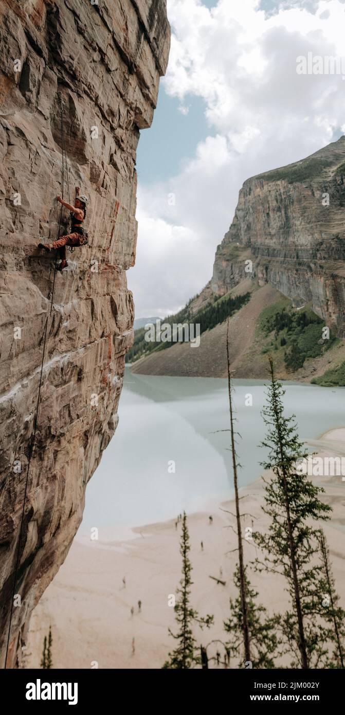 Il primo piano di una donna adulta arrampicatrice su una scogliera vicino a un lago Foto Stock