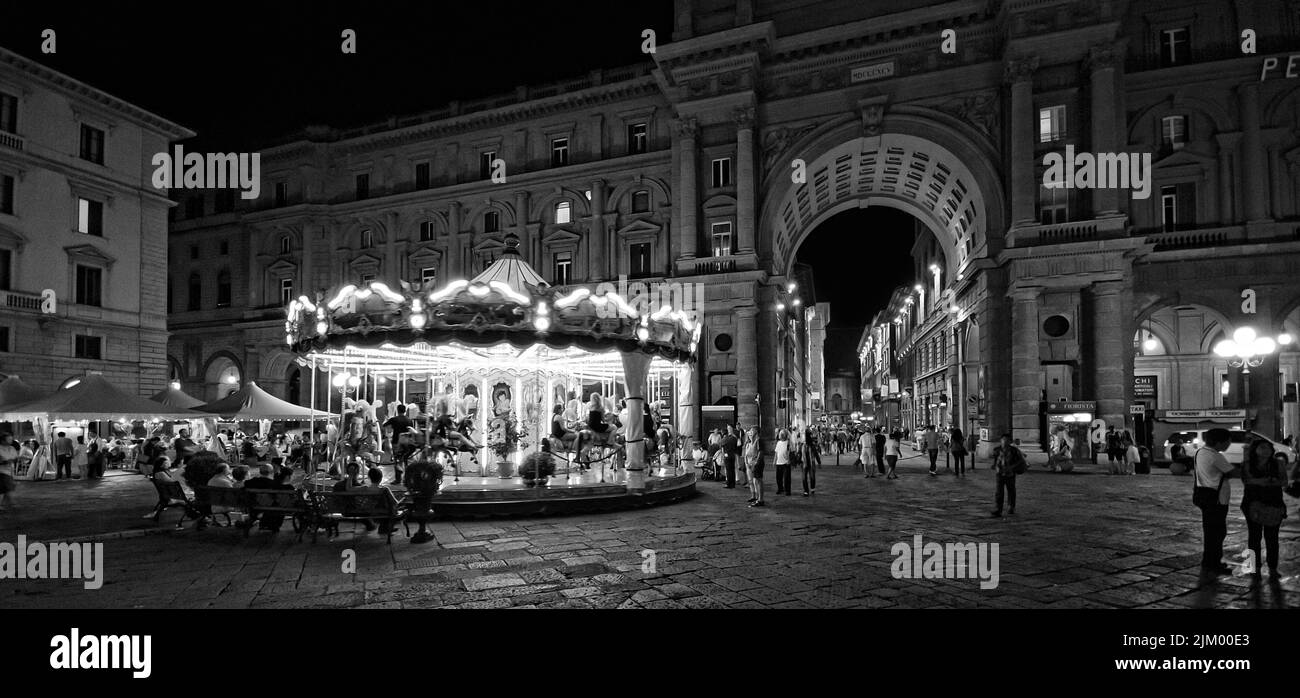 Una foto in scala di grigi di un allegro giro in piazza di notte a Firenze Foto Stock