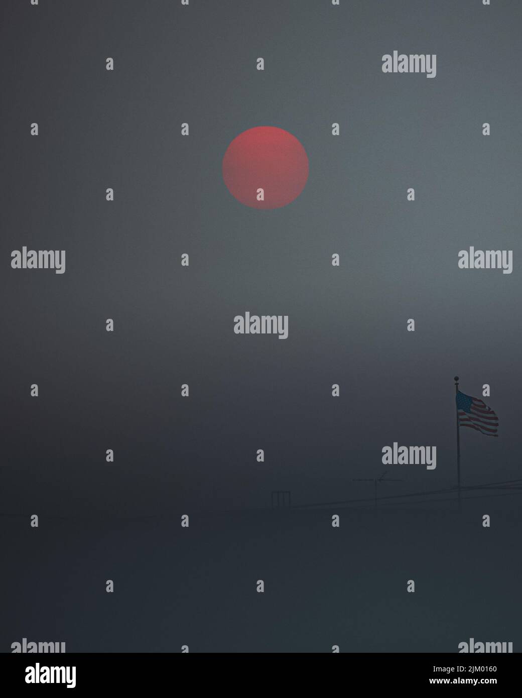 La bandiera americana sventola all'aperto in una giornata di nebbia con una luna di sangue sullo sfondo Foto Stock