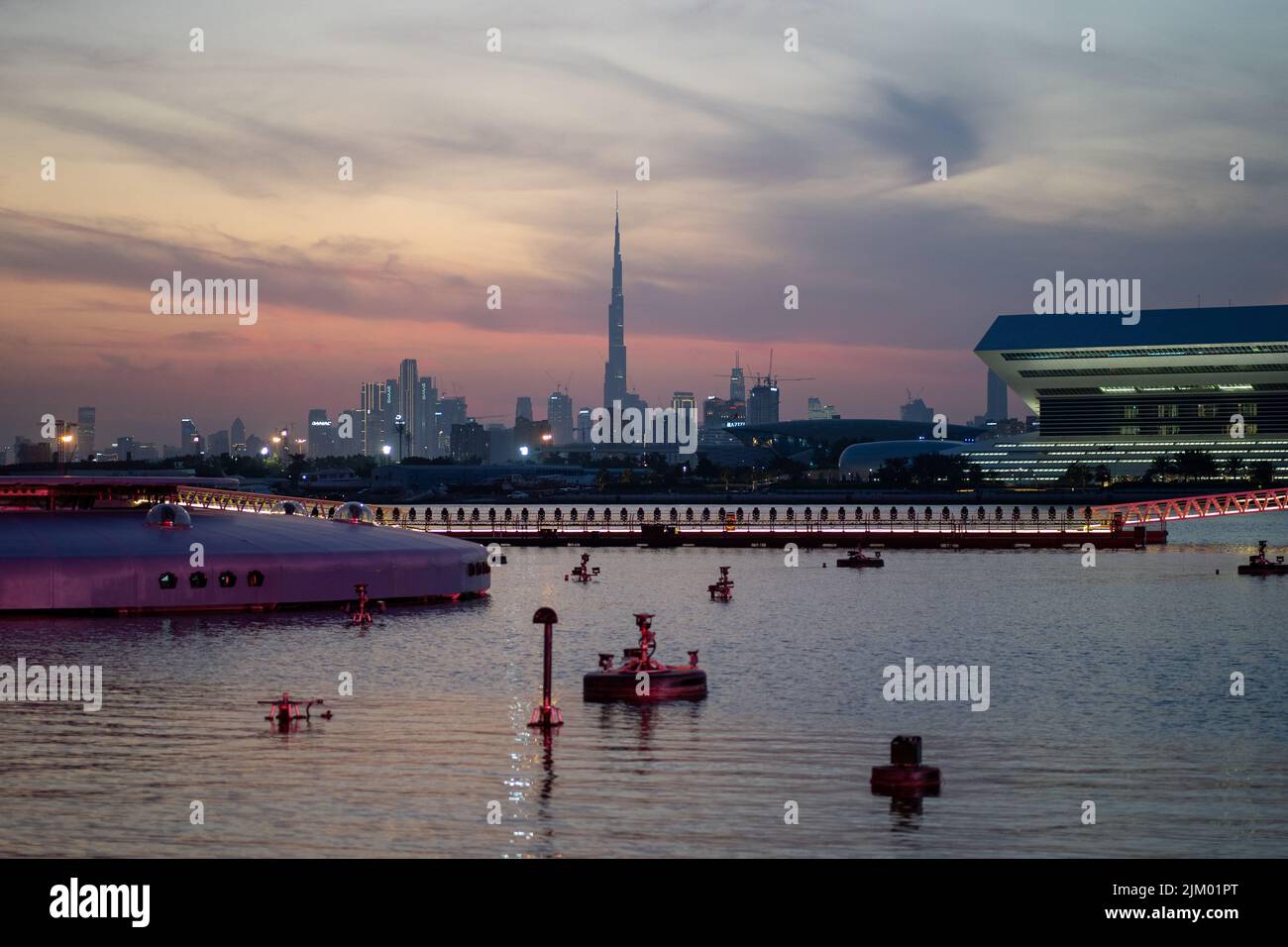 Una vista mozzafiato del Lago Festival City con il paesaggio urbano di Dubai sullo sfondo del cielo al tramonto Foto Stock
