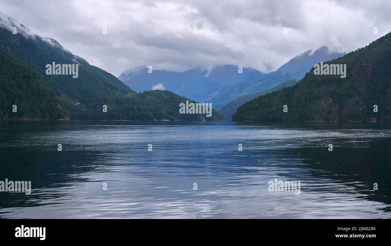 Guardando giù una lunga insenatura nord-occidentale del Pacifico in una giornata noosa come le nuvole rotolano giù le montagne lontane. Foto Stock