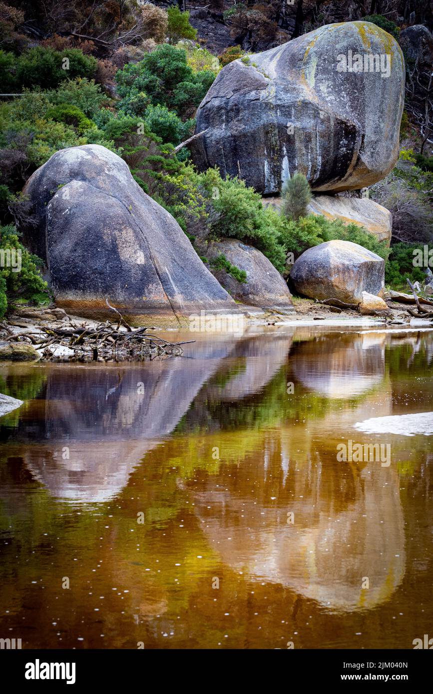 Un colpo verticale di Tidal River che riflette enormi rocce sulla riva del promontorio di Wilsons, Australia Foto Stock