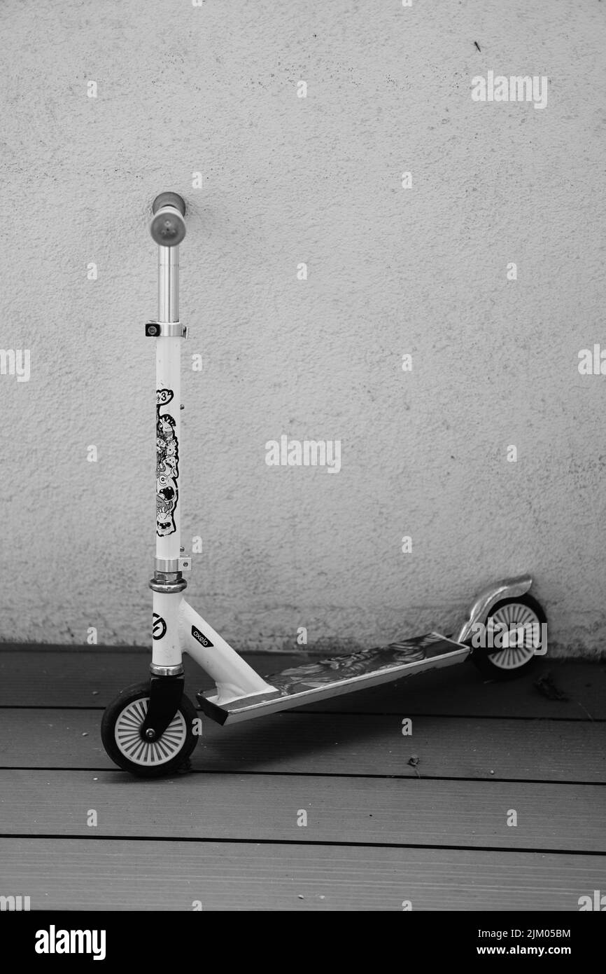 Una foto verticale di uno scooter per bambini del marchio Oxelo Decathlon su tavole di legno grigie Foto Stock