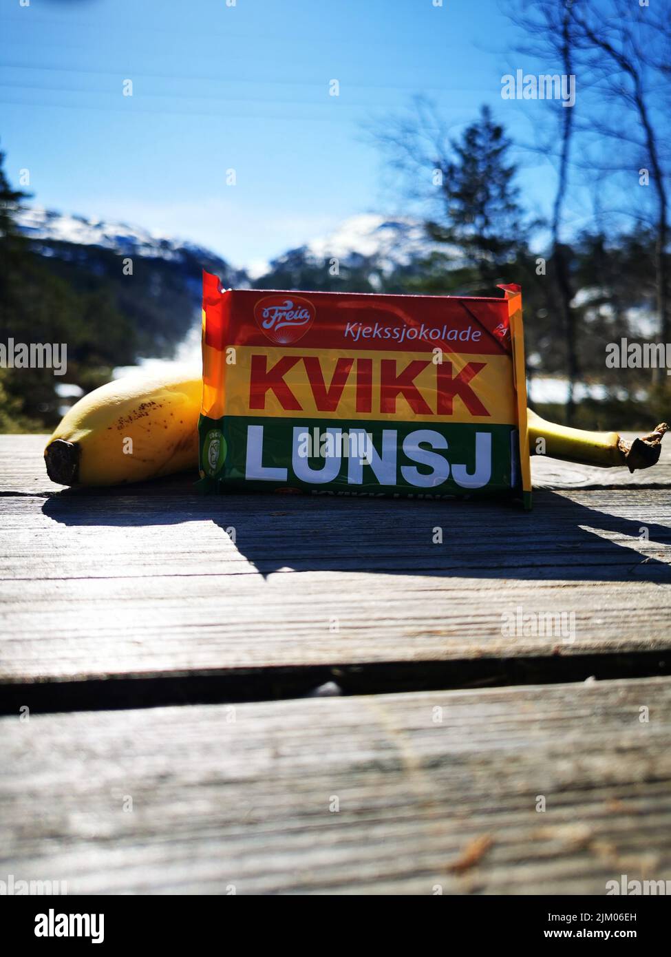 Un bicchierino verticale di un cioccolato Norwegian Quick Lunch di Freia e una banana su una panchina Foto Stock