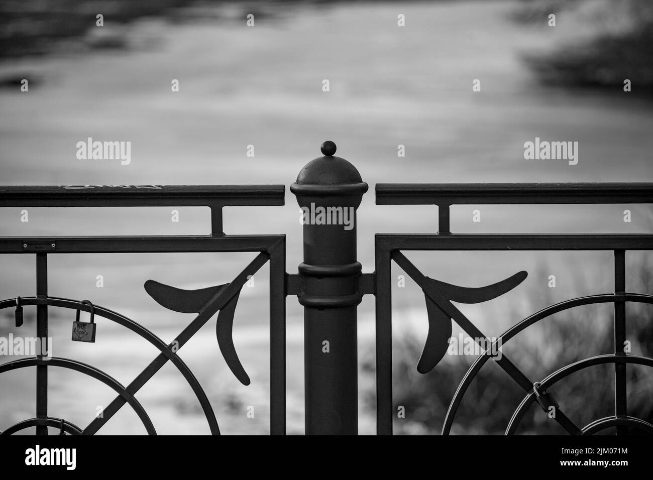 La scala di grigi di una recinzione ponte con una vista sul fiume sullo sfondo Foto Stock