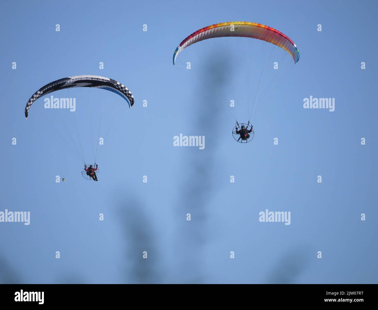 Un primo piano di due parapendio che volano con un cielo blu sullo sfondo Foto Stock