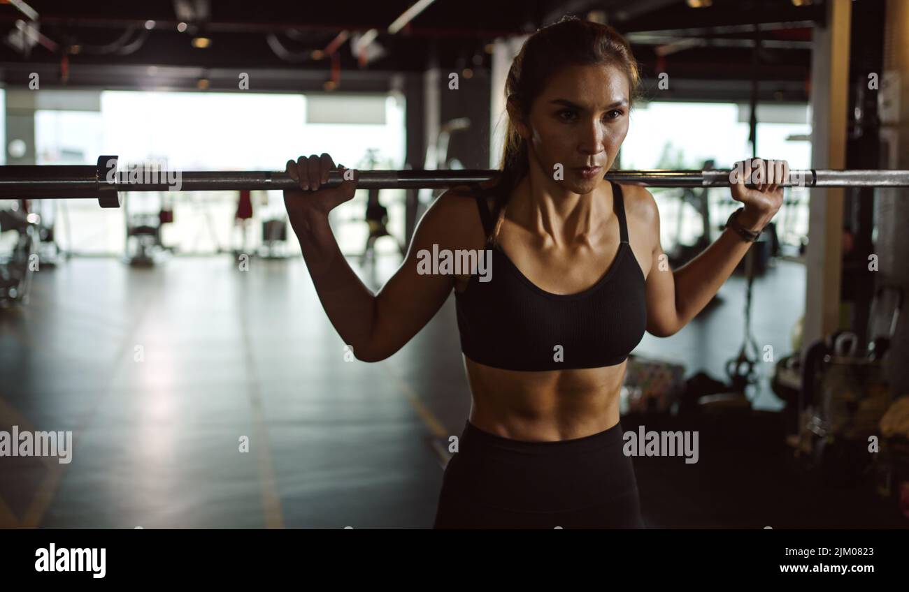 Donna sportiva che si esercita con il barbell in classe di fitness. Donna in palestra con barbell. Foto Stock