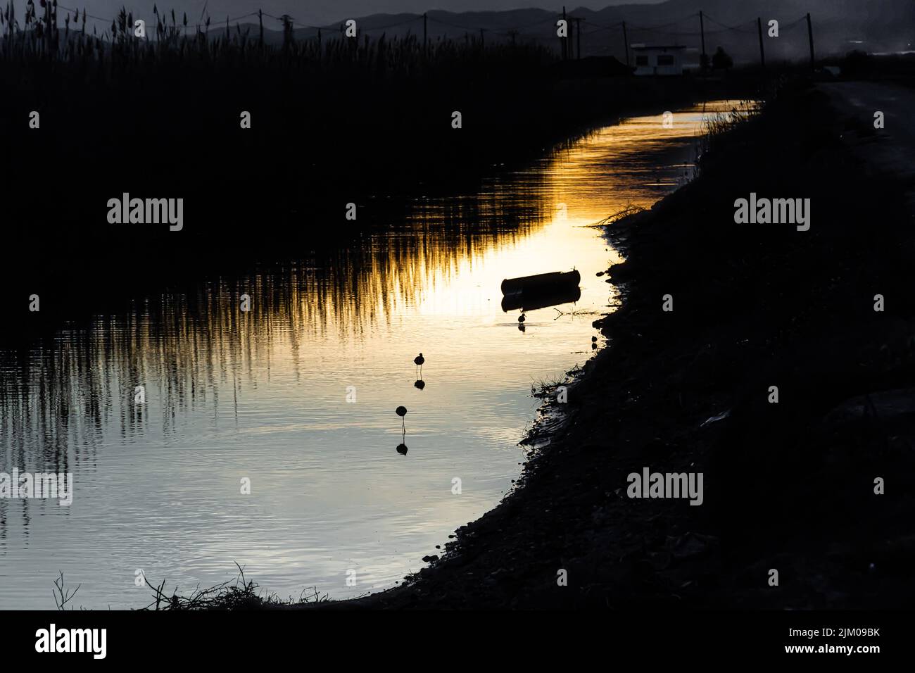 Una vista panoramica di un fiume con riflessi tramonto in una zona rurale Foto Stock