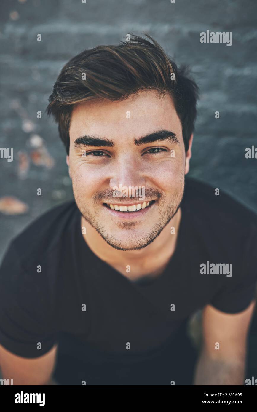 Ridendo, felice e sorridente volto di uno studente isolato contro un muro grigio della città fuori. Ritratto e colpo di testa di un giovane elegante, fresco e funky Foto Stock