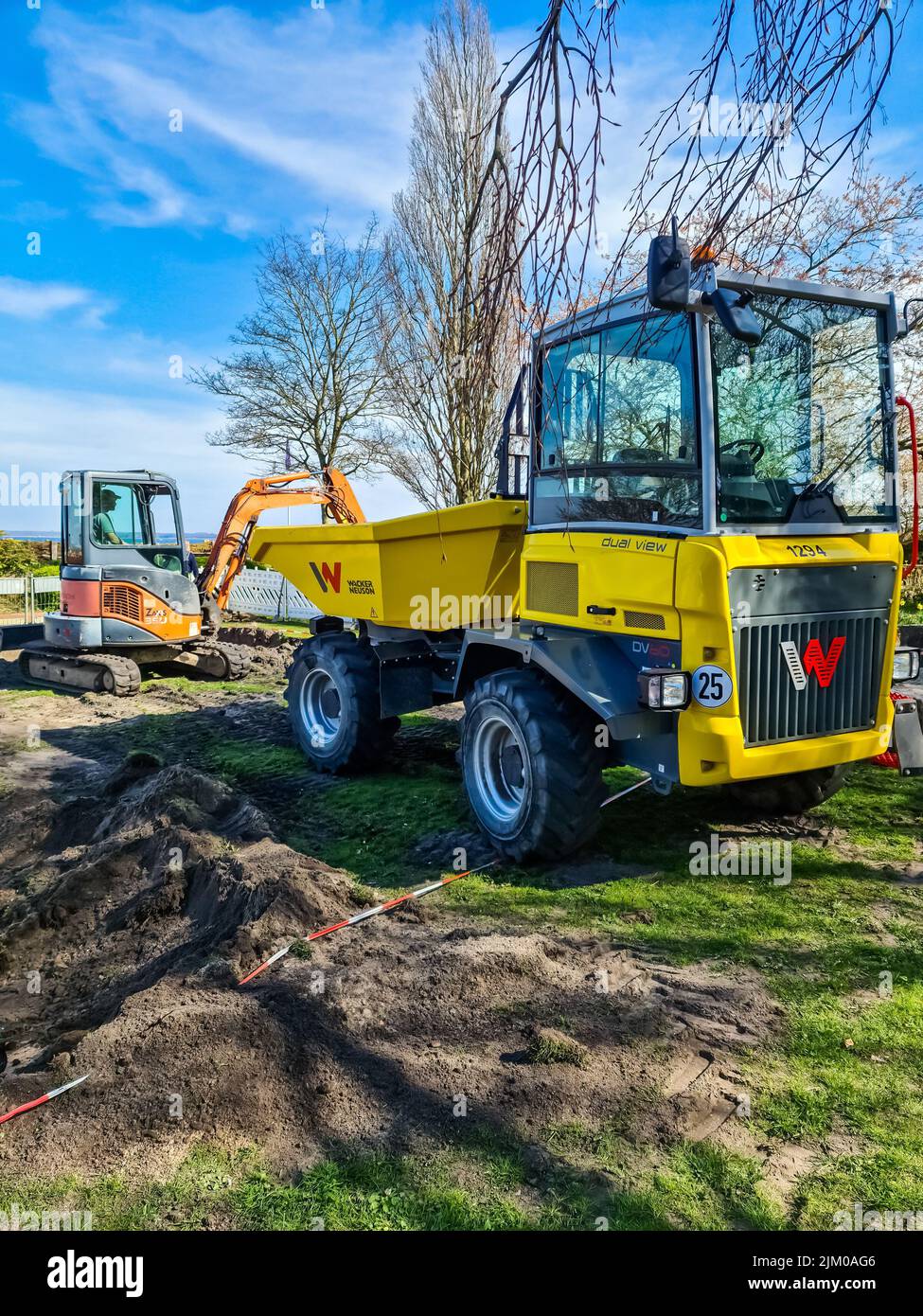 Uno scatto verticale di un piccolo escavatore e di un camion del marchio Wacker Neuson sulla spiaggia di Eckernforde. Germania. Foto Stock