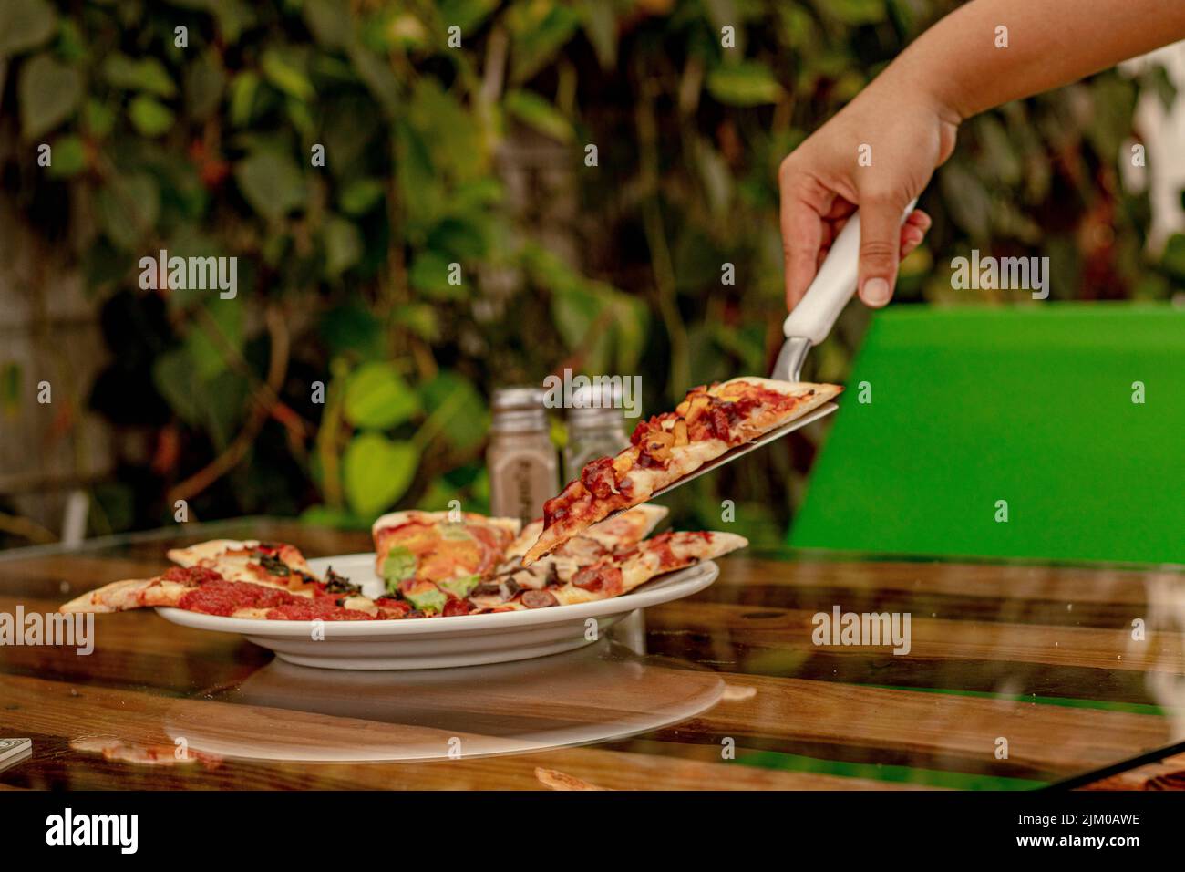 Un primo piano della mano che prende una fetta di pizza da un servitore di pizza. Foto Stock