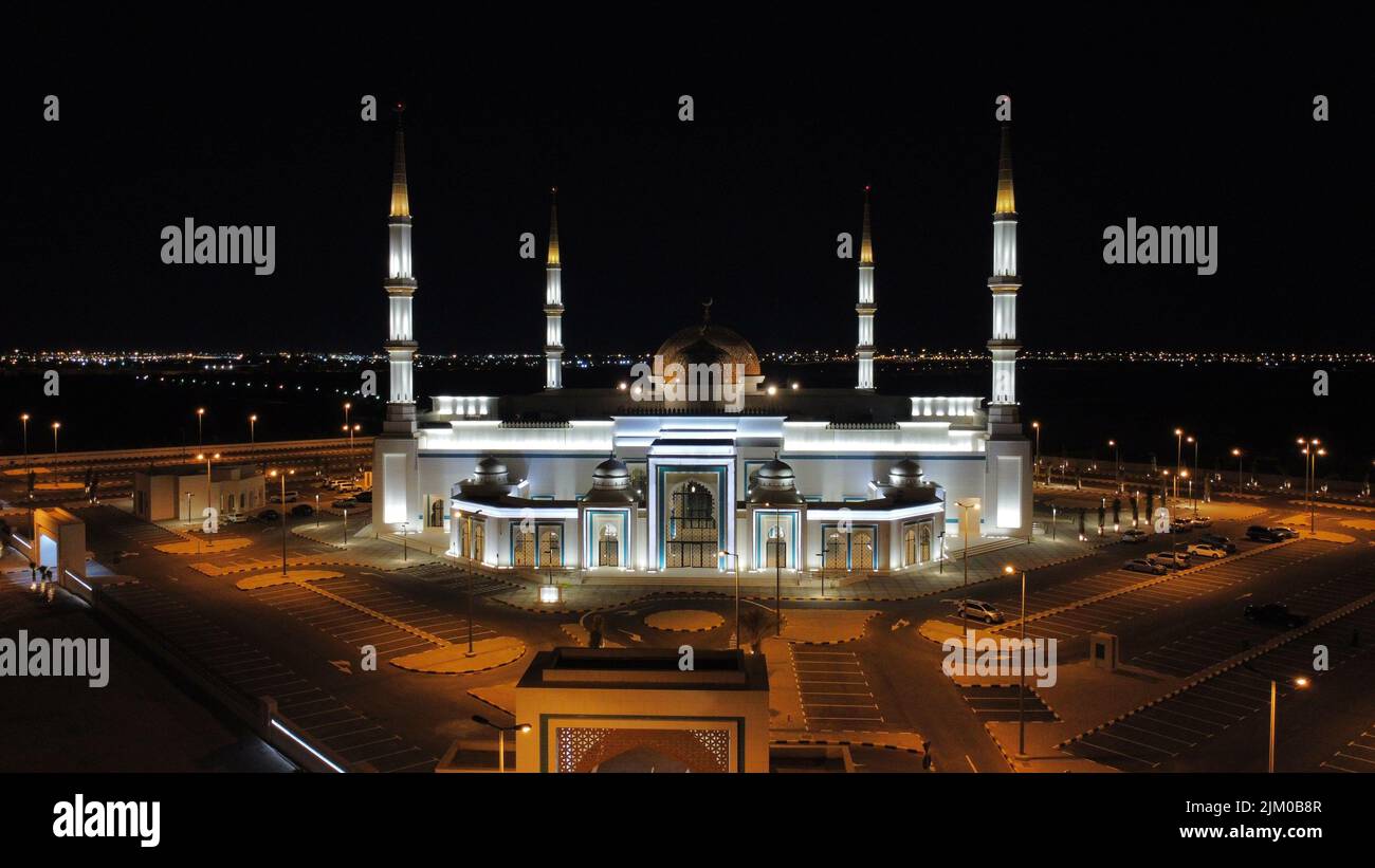 Una vista notturna di al Ghanim Masjid con le luci al cimitero di Sulaibikhat Foto Stock
