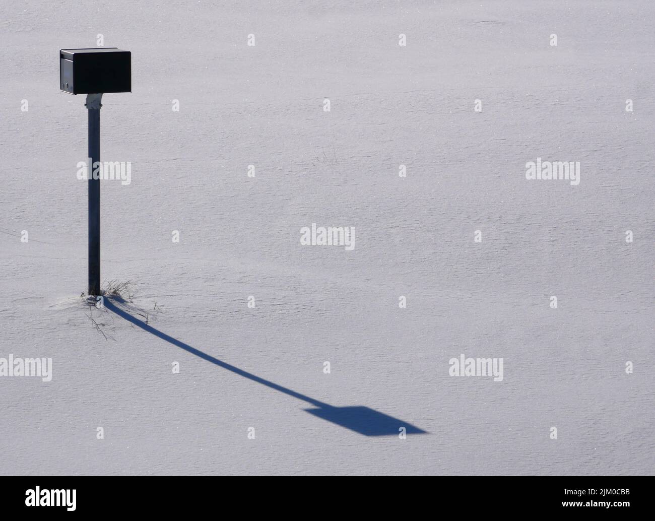 palo di ricarica per auto elettriche nella neve con ombra Foto Stock