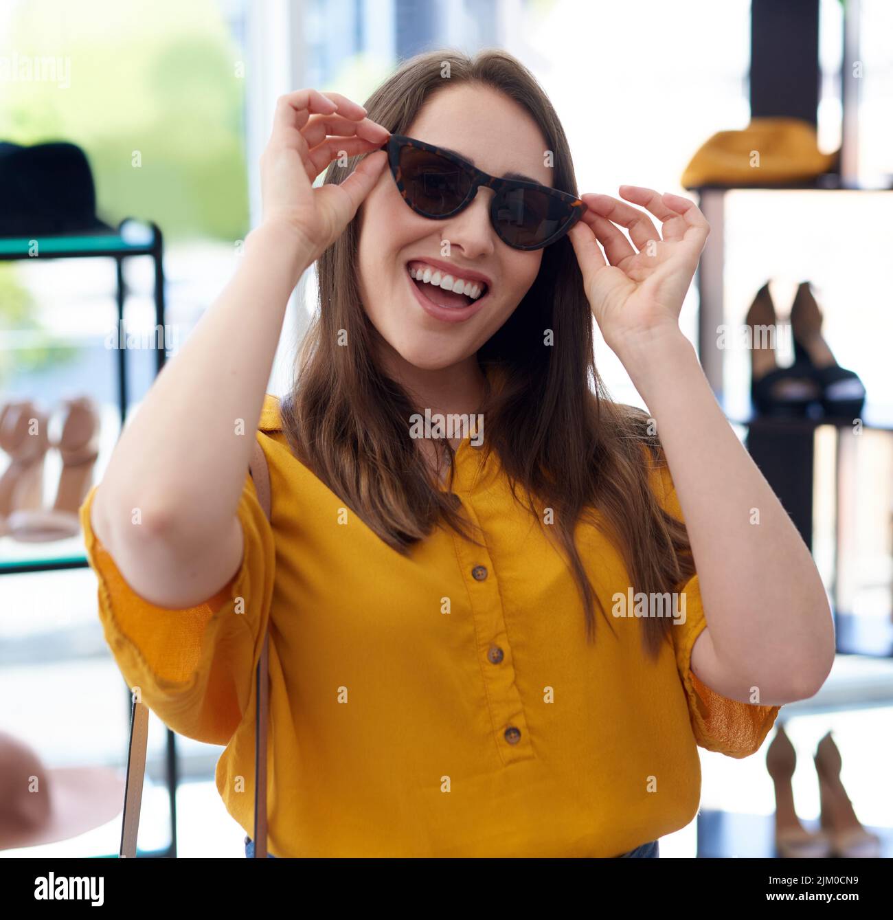 Im sempre pronto per una terapia al dettaglio. Ritratto di una giovane donna che cerca di occhiali da sole mentre fa shopping in un negozio. Foto Stock