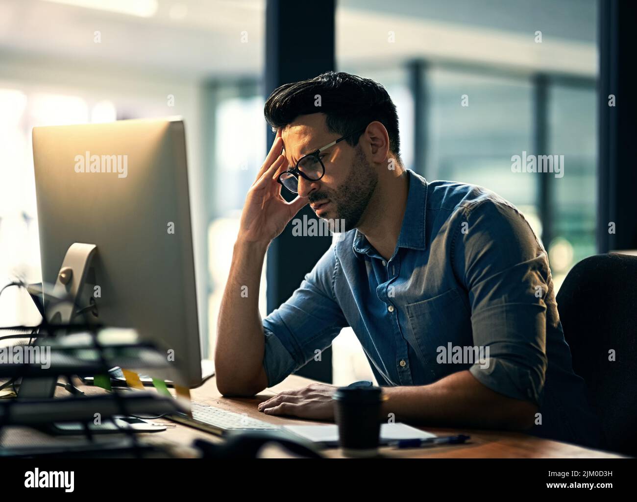 È ancora finita la settimana. Shot di un giovane uomo d'affari che sperimenta stress durante una notte tarda al lavoro. Foto Stock