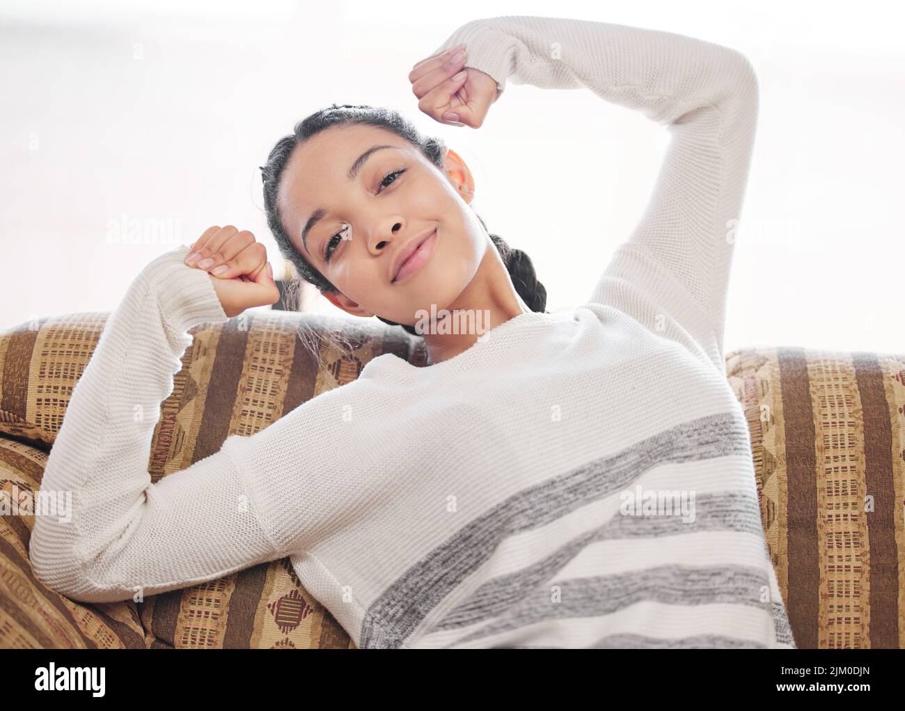 Rallentare e immergerlo. Una giovane donna che si rilassa sul divano di casa. Foto Stock