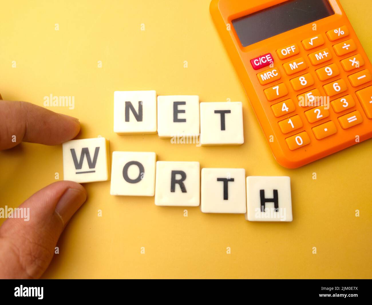 Mano che tiene giocattoli parola con la parola NET WORTH. Foto Stock