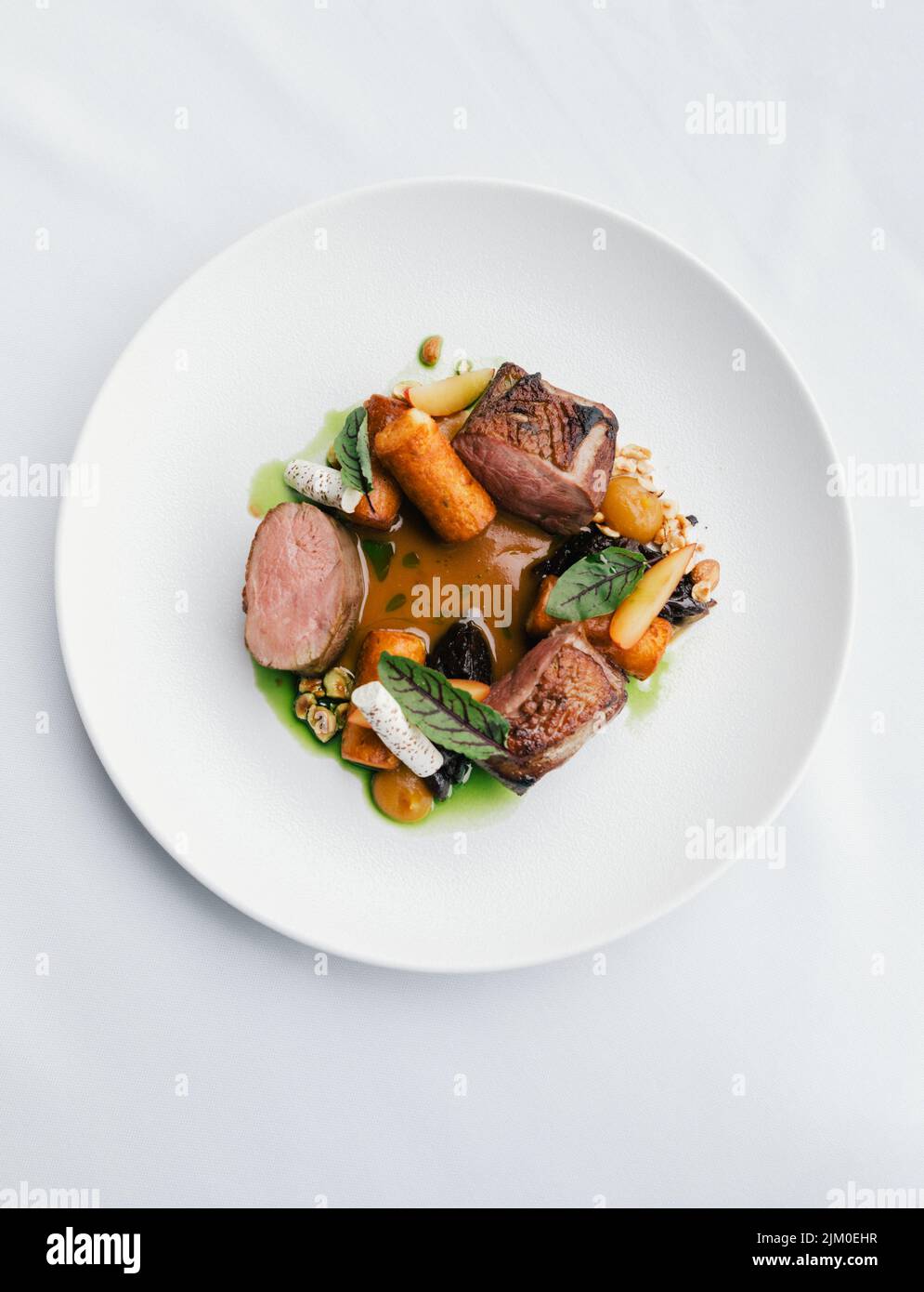 Uno shot verticale di un piatto gourmet con carne, verdure e salsa Foto Stock