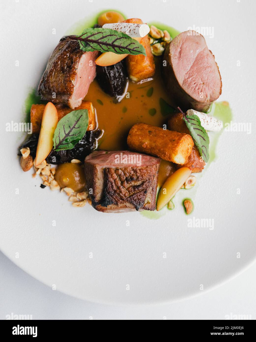 Un primo piano verticale di un piatto gourmet con carne, verdure e salsa Foto Stock